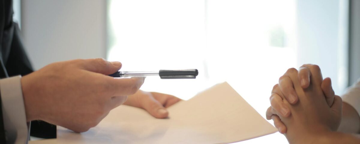 Close-up of a contract signing with hands over documents. Professional business interaction.