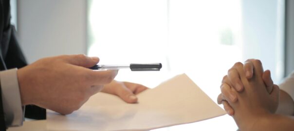 Close-up of a contract signing with hands over documents. Professional business interaction.